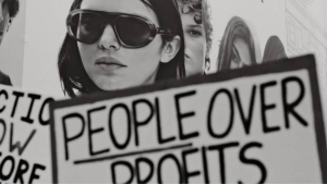 Woman holding sign people over profits