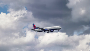 A Delta Air Lines airplane flying through a cloudy sky, with its landing gear extended, appearing to approach for landing.