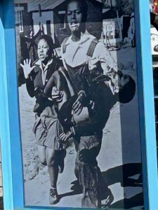 Sam Nzima's historical photo of Mbuyisa Makhubu carrying Hector Pieterson alongside Antoinette.