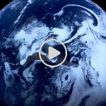 Planet Earth visible as a whole blue marble with white cloud swirls against the black background of space, taken from a video screen.
